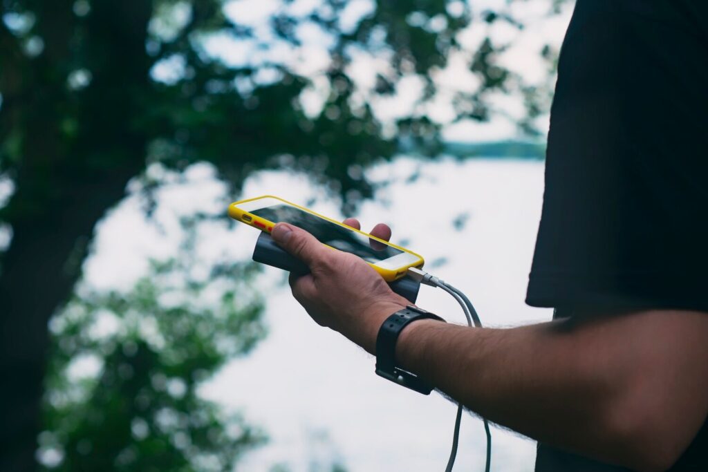 Guy is holding portable charger with smartphone his hand man background nature with greenery lake 115838 735